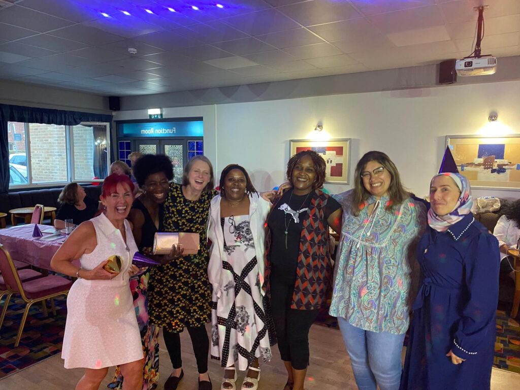 Women of Wythenshawe celebration event group of women laughing and smiling in a conference room